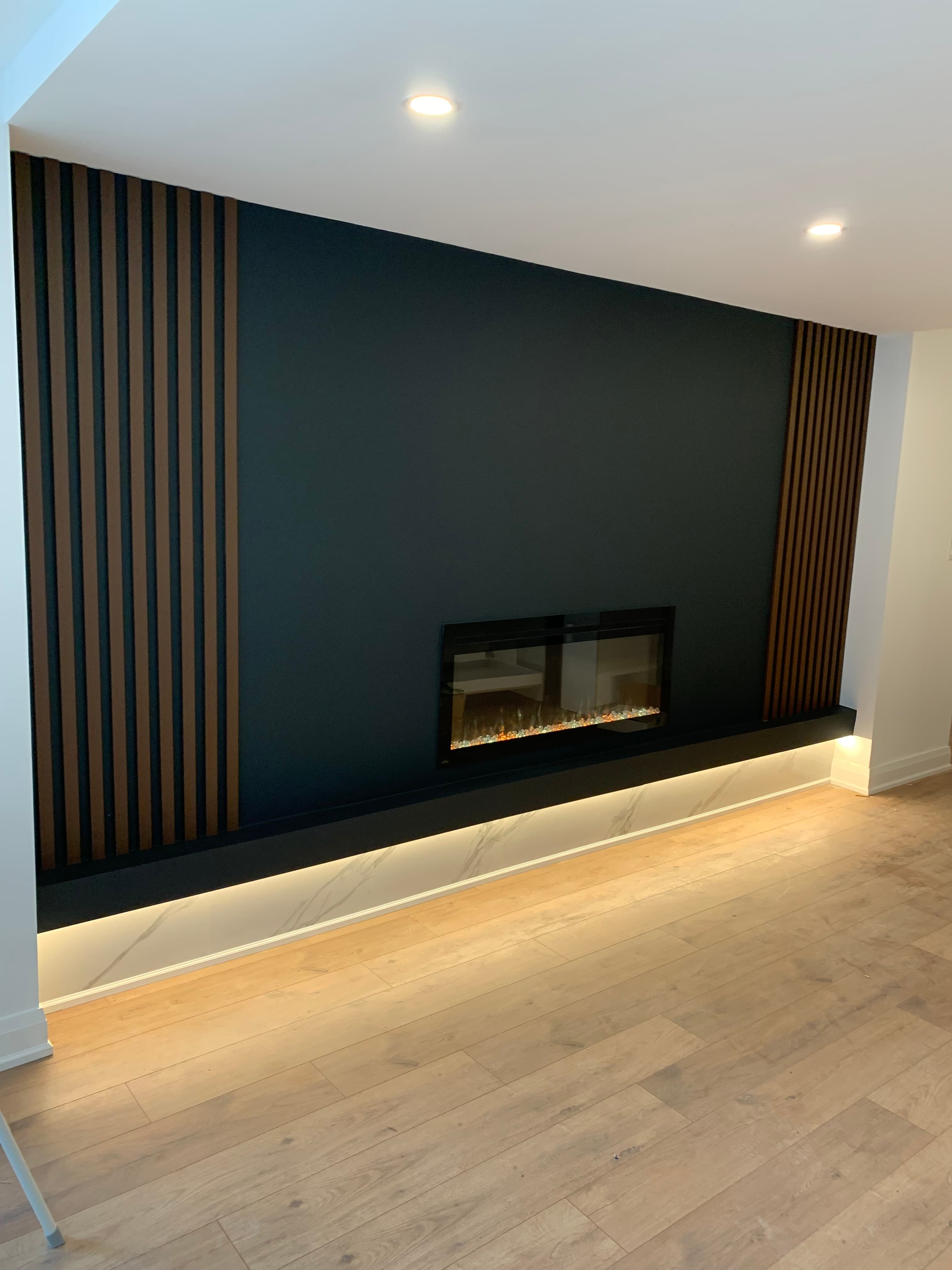 Warm accent lighting installed beneath a modern fireplace feature wall